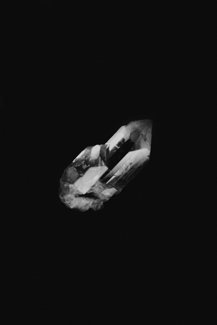 Elegant black and white photo of a crystal against a dark backdrop, highlighting its natural beauty and geometry.