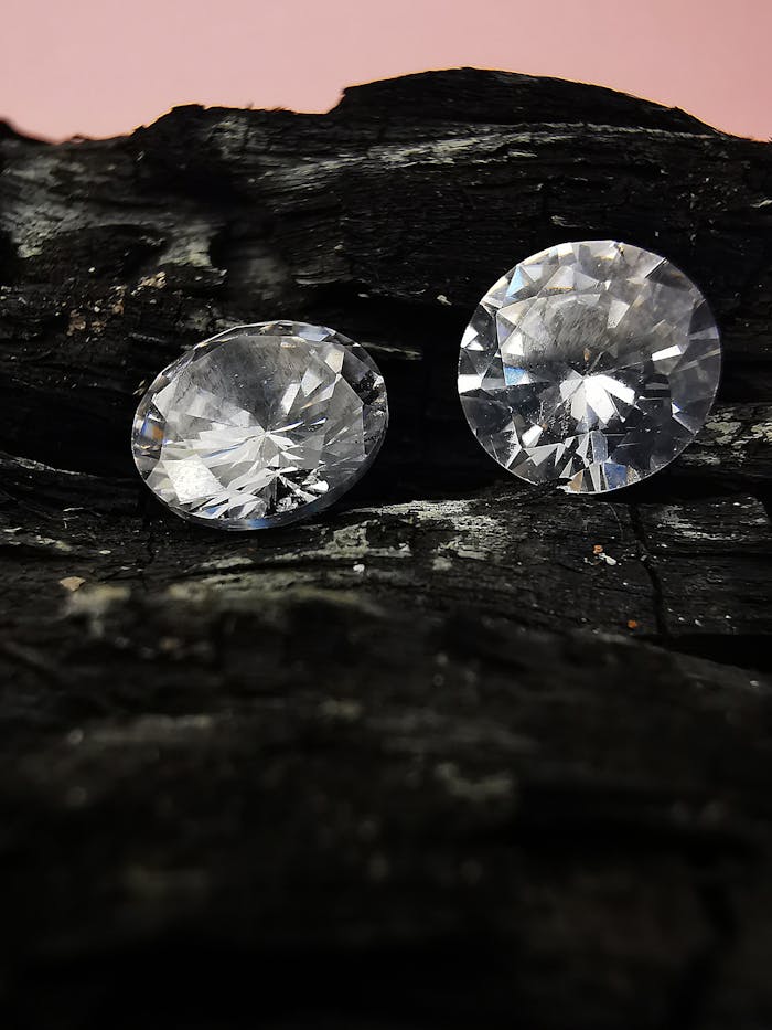 Close-up of two dazzling gems on a textured charcoal surface.